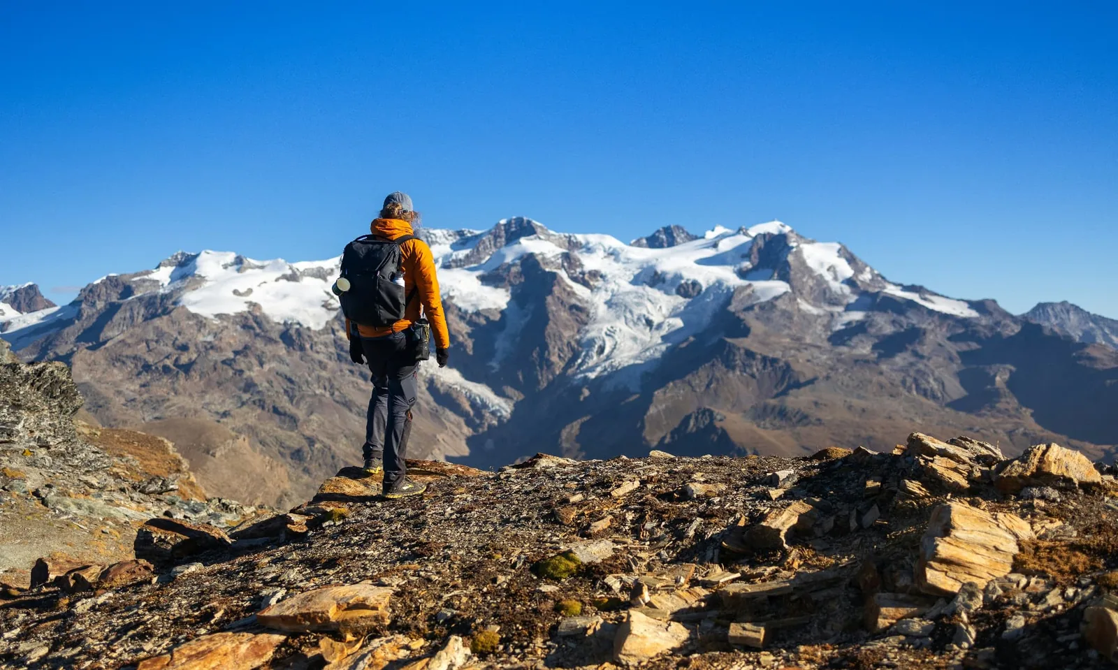 Lone hiker looking across a broad snow-capped mountain range