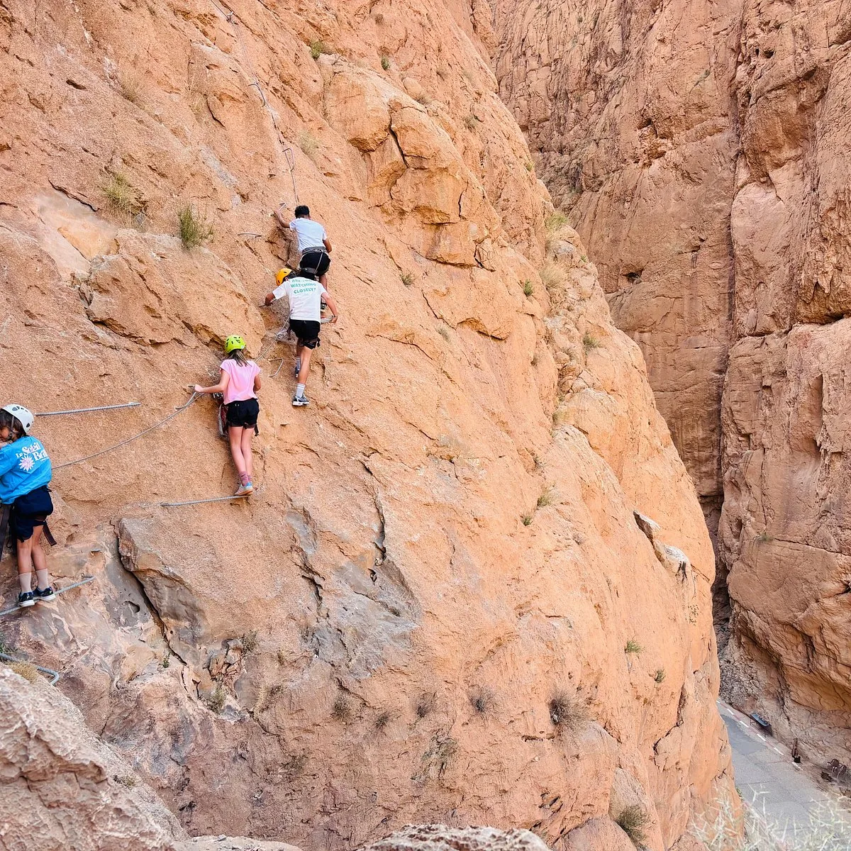 Epic Monkey Fingers Trek: hikers following a protected path across a salmon-coloured canyon wall